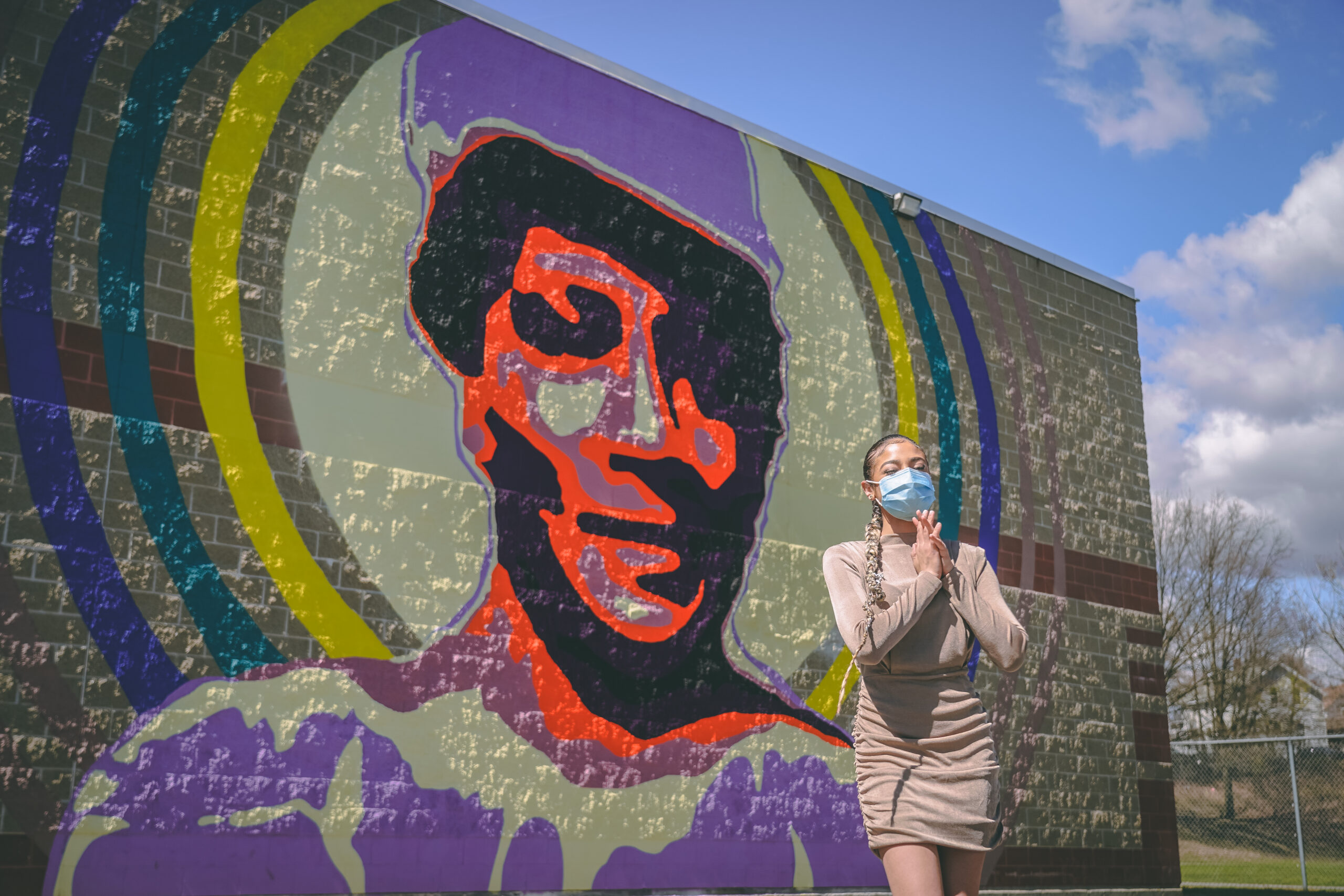 photo of a mural with the artist standing in front