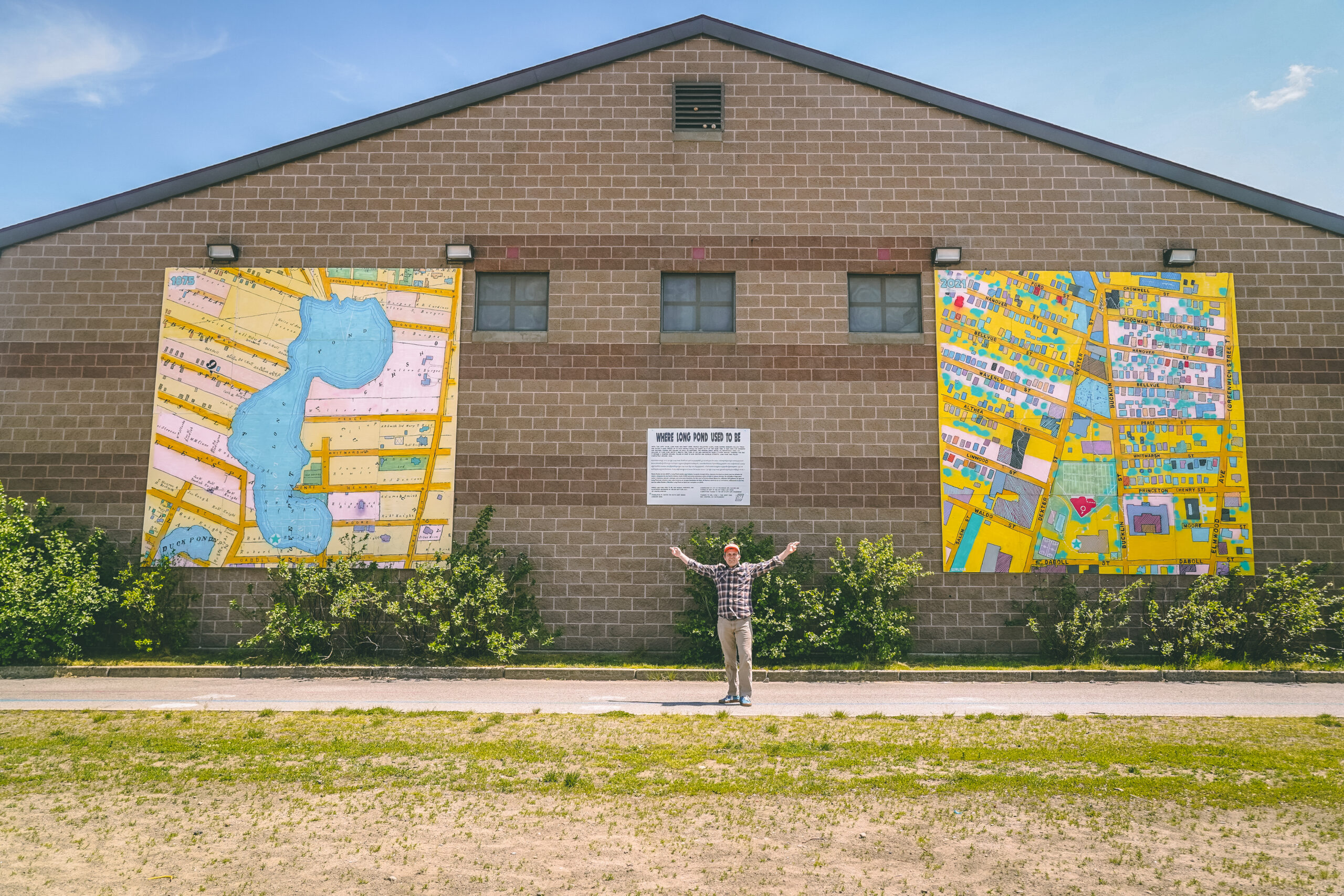 photo of art installation on the side of the building with the artists standing next to it