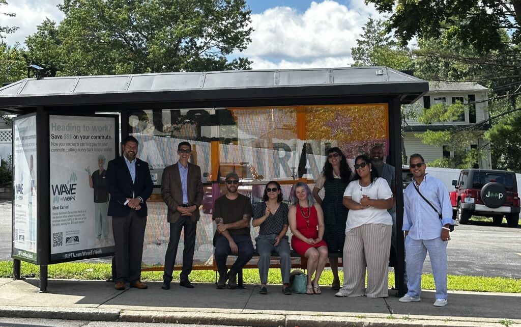 Elected officials, City workers and the artist Greg Pennisten pose in front of a bus shelter with his mural on it dedicated to Admiral St. 