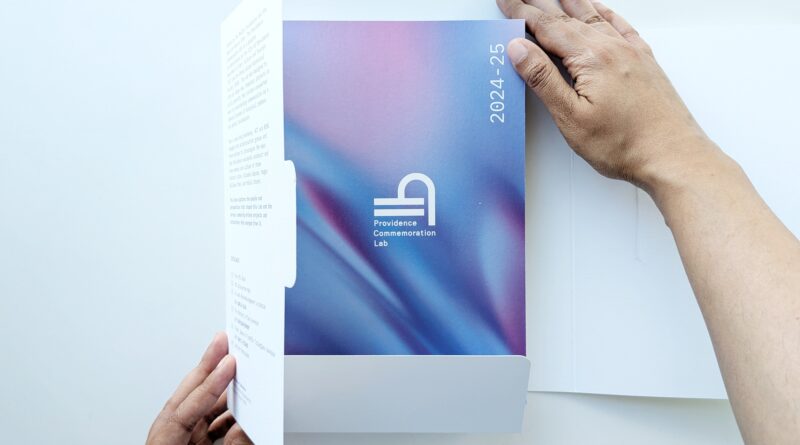 Two hands holding a book emerging from a paper box